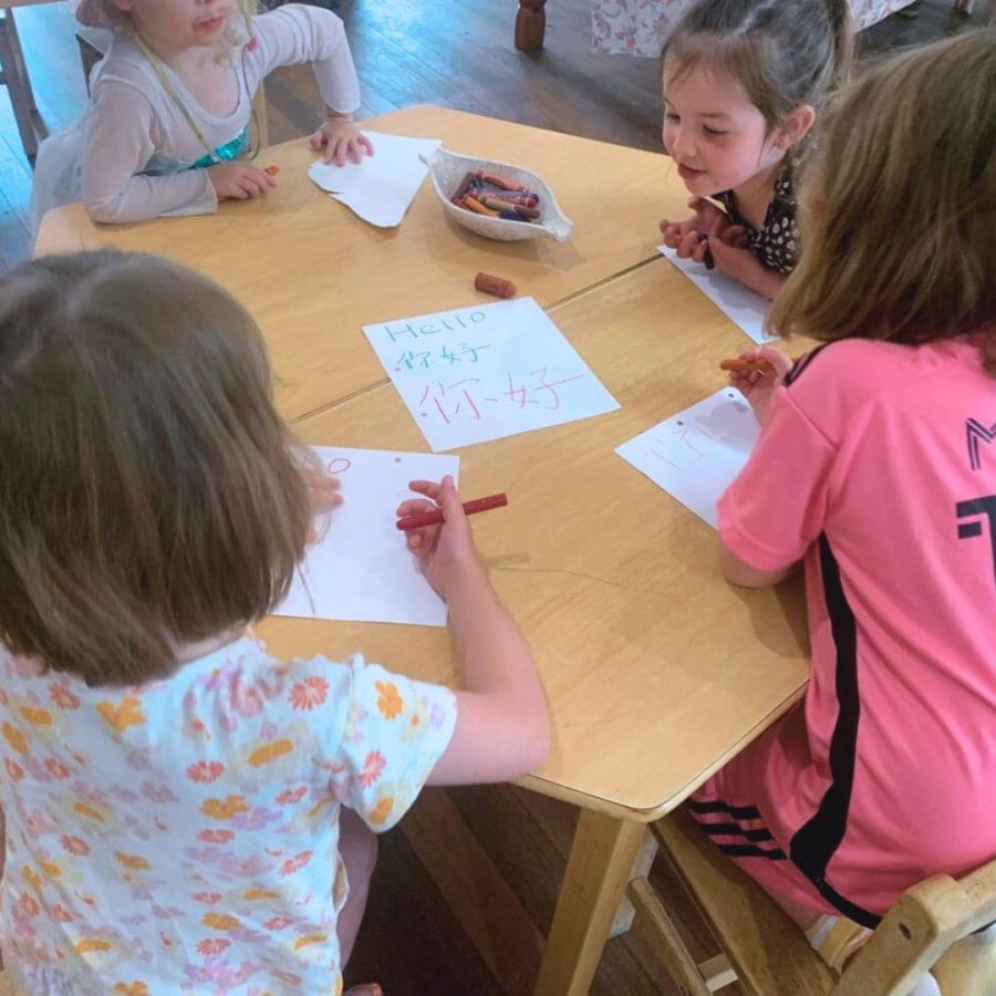 Children practising writing 'hello' using Chinese characters